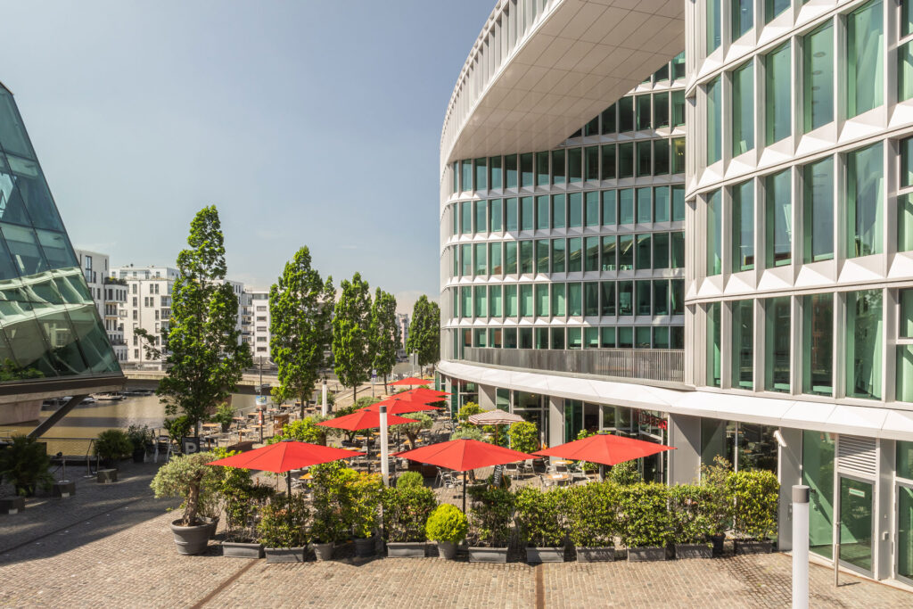 Blick auf das Westhafen Haus mit Außenbereich des Restaurants L'Osteria