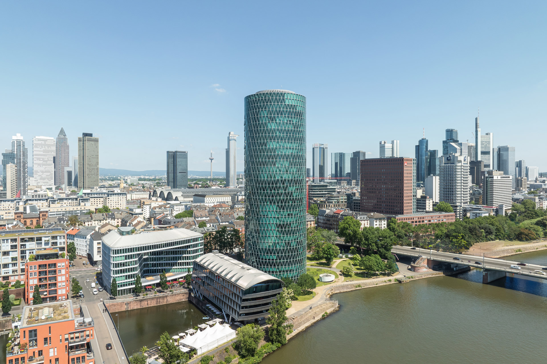 Luftbild des Westhafen Ensembles (Westhafen Tower, Westhafen Haus, Westhafen Brückengebäude) vor der Skyline der Stadt Frankfurt am Main